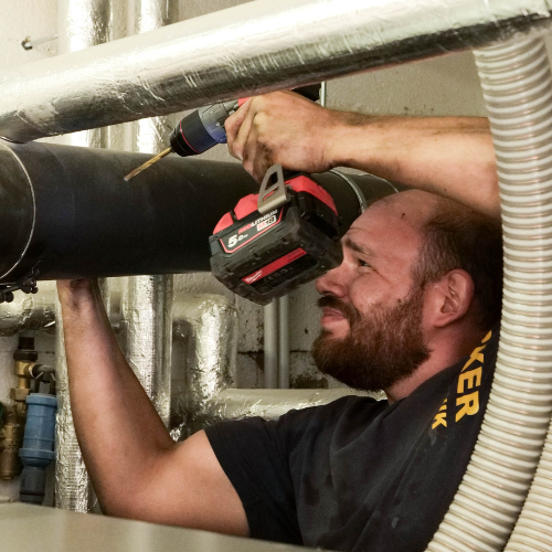 Handwerker bohrt in ein Rohr mit Schraubmaschine.