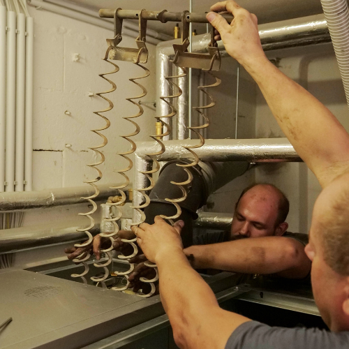 Männer reparieren Heizungsrohre im Keller