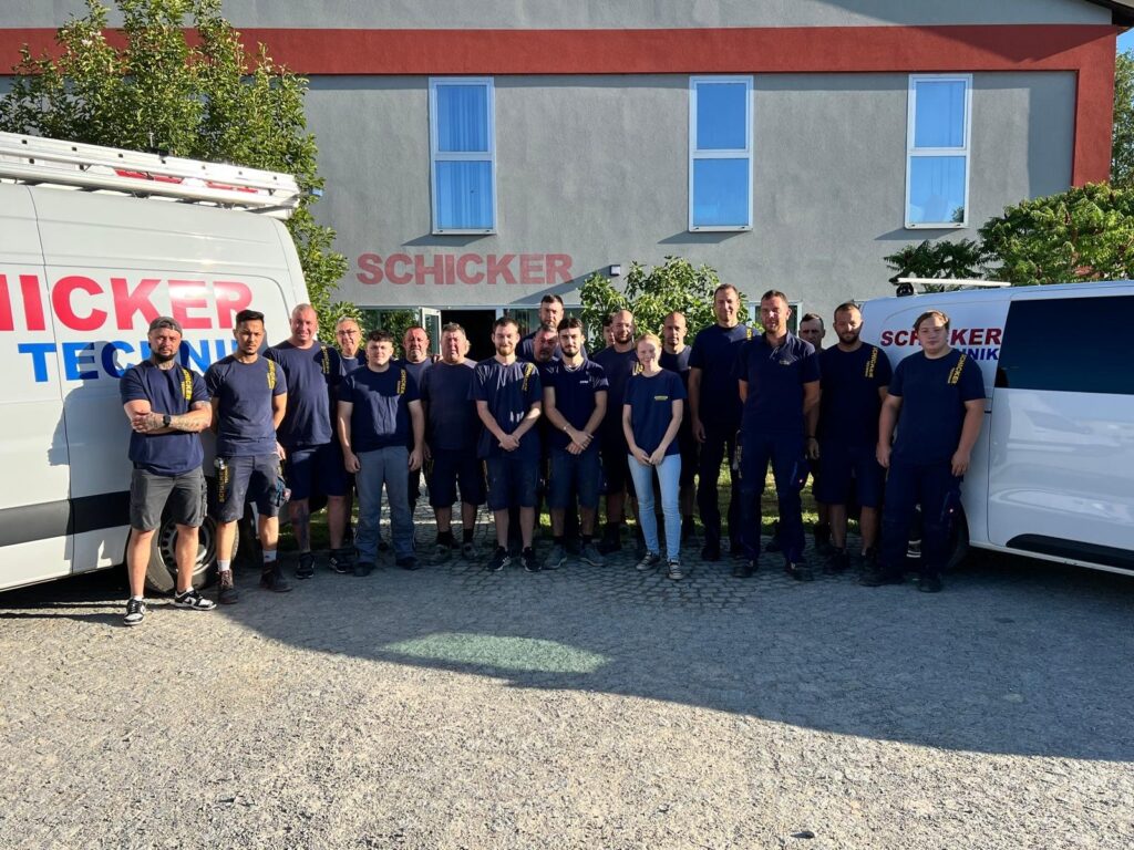 Gruppe von Mitarbeitern vor Firmengebäude und Fahrzeug