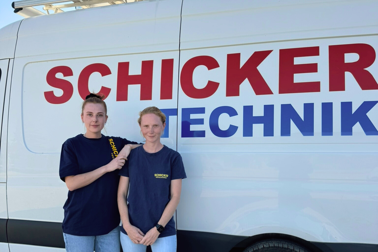 Zwei Frauen stehen vor einem Techniker-Firmenwagen.