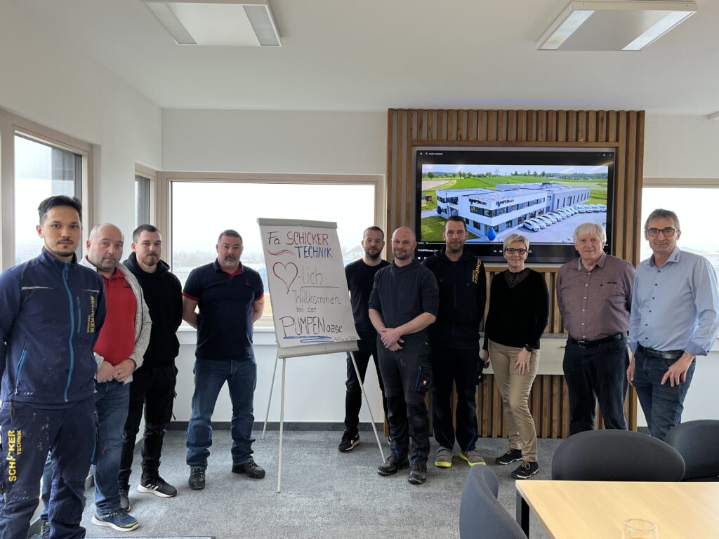 Gruppe vor Flipchart und Bildschirm im Büro.